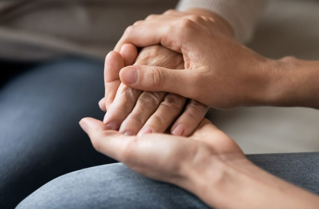 a pair of young hands hold old wrinkled hands in support