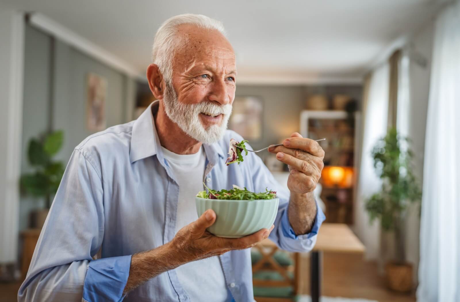 A senior makes healthier food decisions by eating a salad.