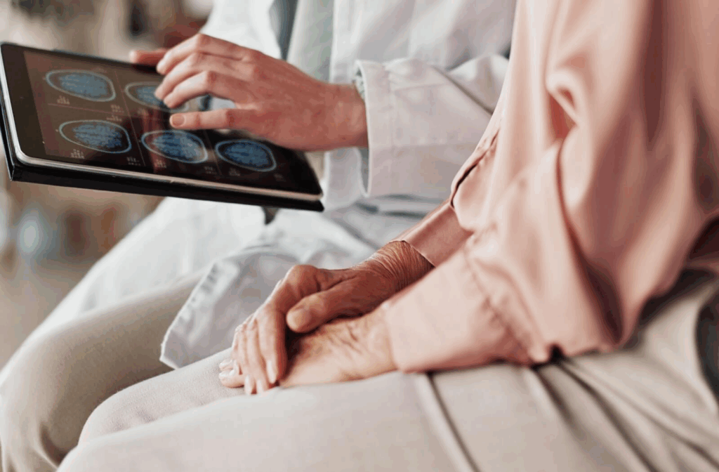 close-up of a doctor with a tablet showing a senior their brain scans, which show signs of cognitive decline, possibly dementia, after going through the FAST Scale.