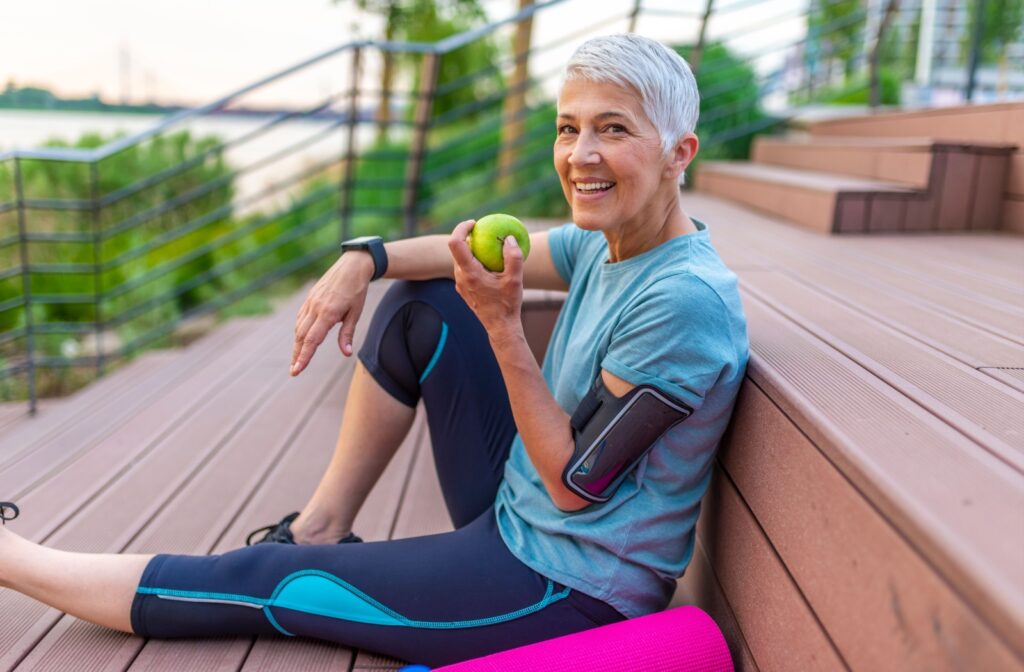 A senior is eating an apple after some exercise and training outdoors.
