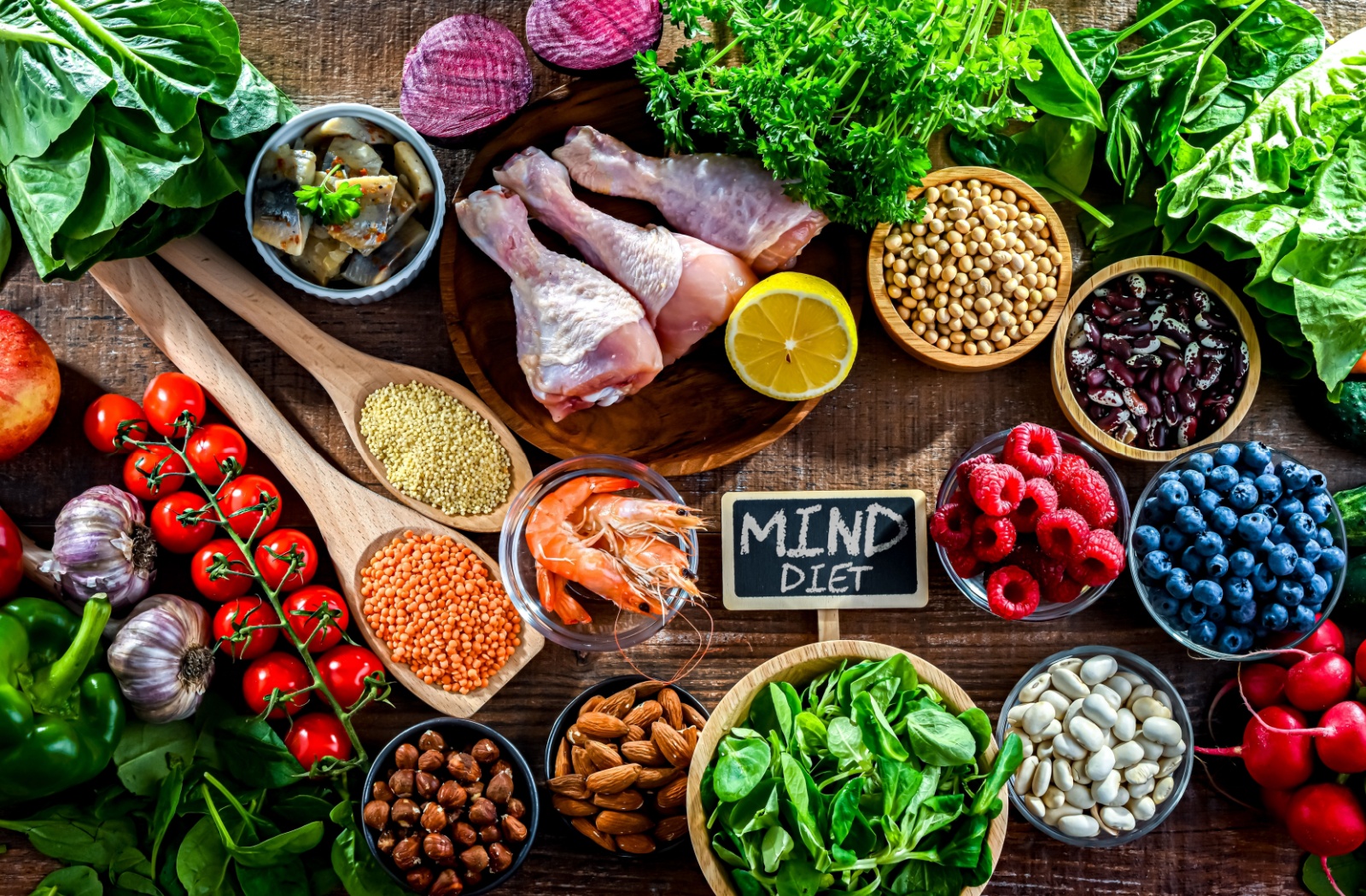 Food products on a table, such as leafy greens, nuts, berries, and grains, represent the MIND diet, which can help reduce dementia and the decline in brain health.