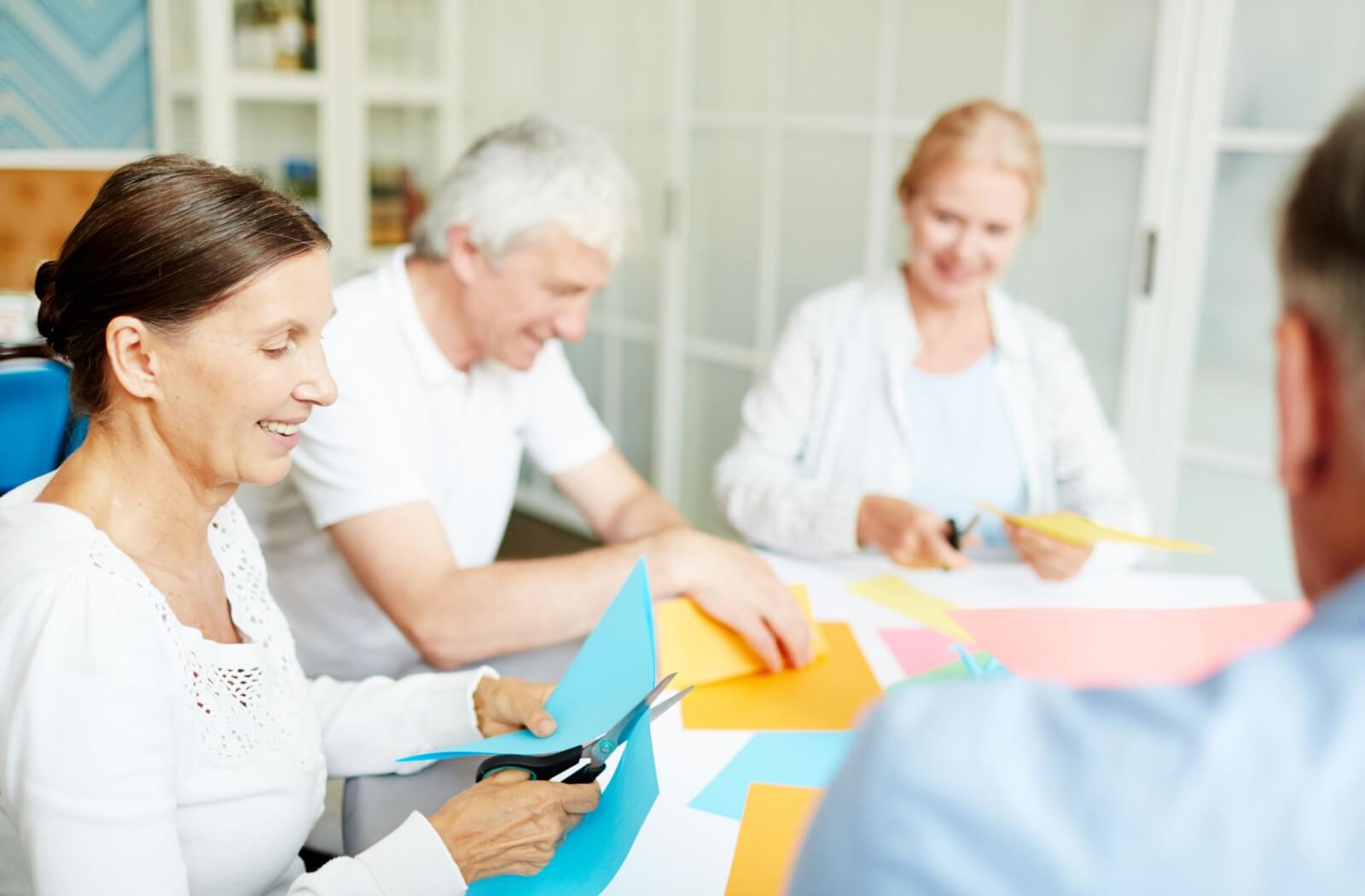 a group of seniors sit at a table doing a craft